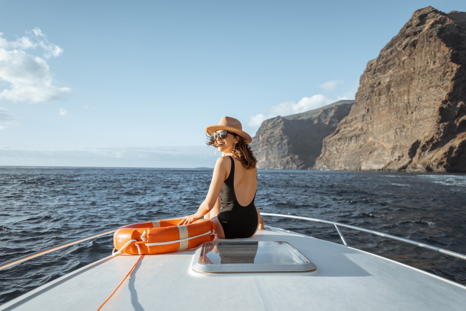 woman sailing on the yacht near the rocky coast