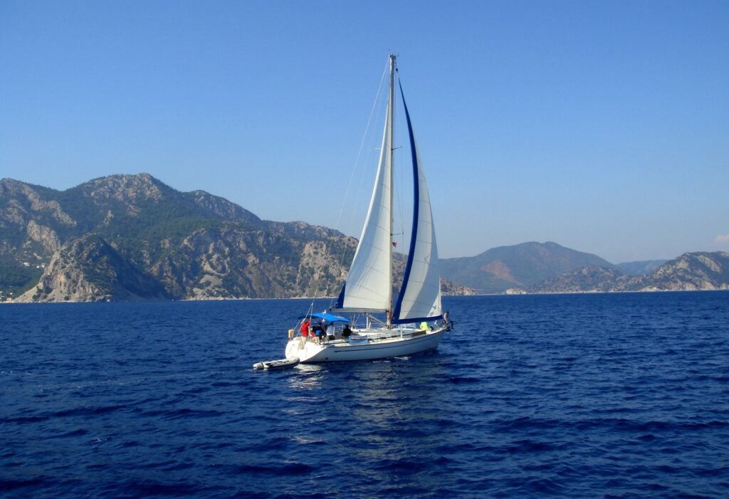 yacht with white sail sailing on a calm sea on a background of mountains